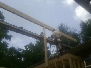 Carpenter setting a ridge beam over a new addition frame — Ice Dam Removal by Roofing Brothers in Smyrna