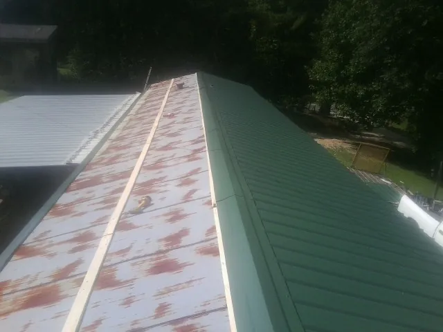 Old rusted panels beside newly installed green metal roofing — Wind Damage Roof Repair by Roofing Brothers in Smyrna