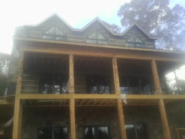 Dormers and porch framing on a large log home under construction — Roof Coating work by our crew in Smyrna