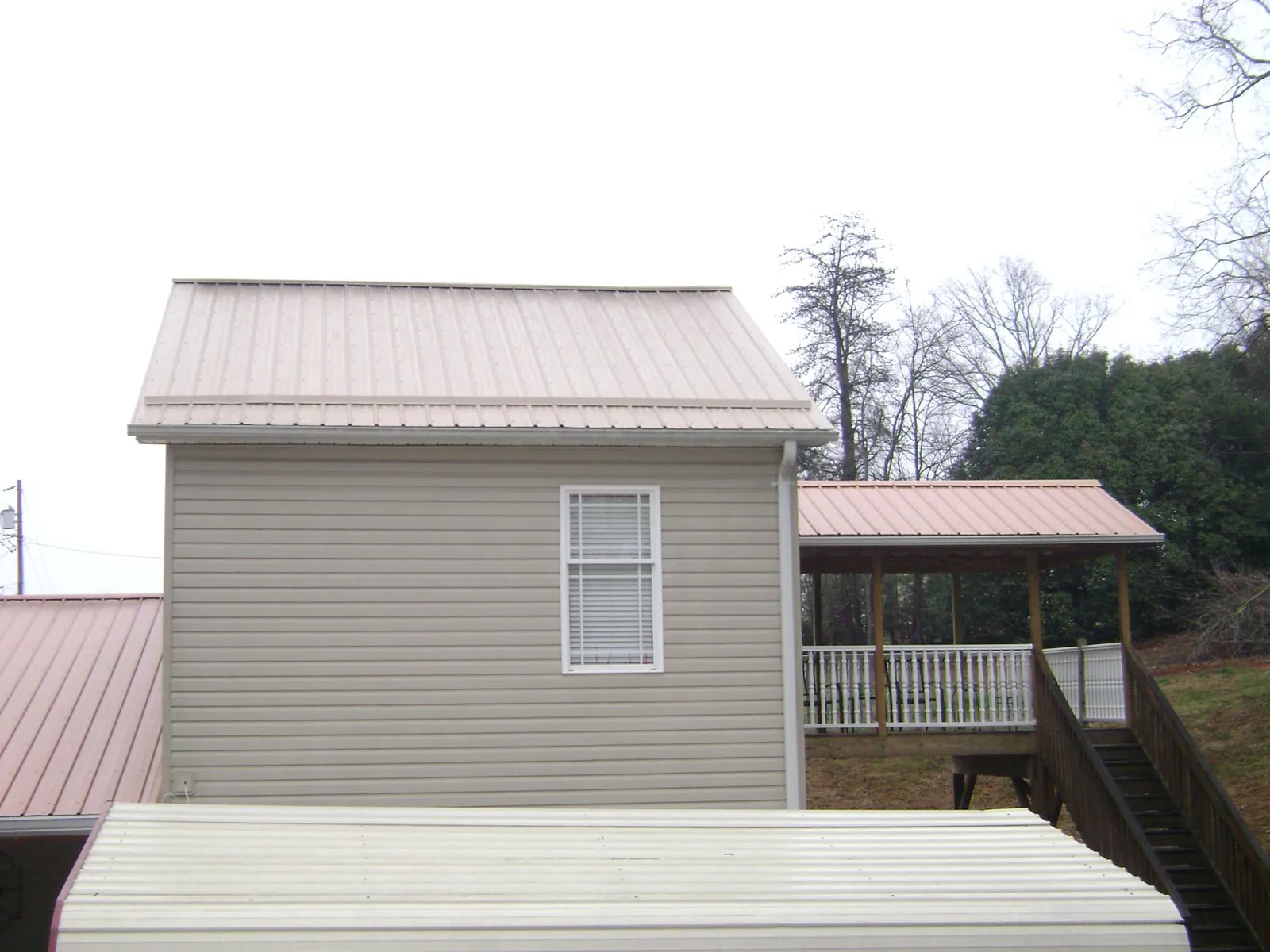 Tan metal roofs on a two story addition and attached porch, from a Roof Replacement job in Smyrna